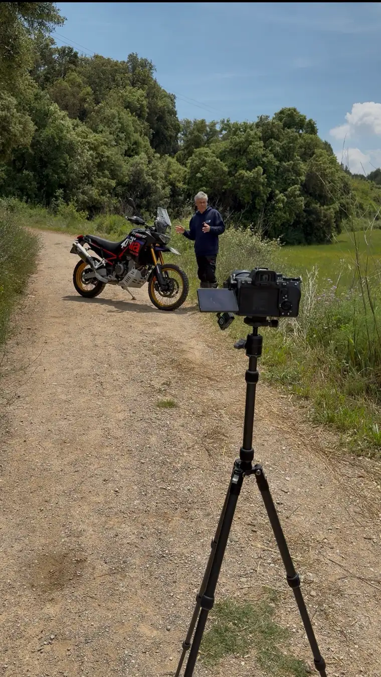 Preparación de una sesión fotográfica de una moto de trail con cámara y trípode en un camino